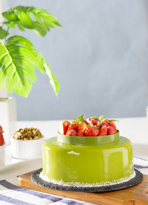 Free From above of yummy mousse cake with colorful mirror glaze and festive decor with strawberries and mint leaves Stock Photo