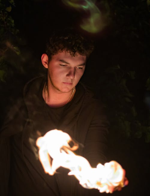 Free Man in Brown Hoodie Jacket Holding a Flaming Material Stock Photo