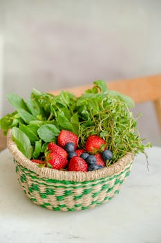 在大理石表面，放着一个装满草莓、蓝莓和新鲜蔬菜的柳条篮