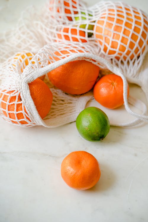 Free Close-Up Photo of Tropical Fruits in a White Mesh Bag Stock Photo