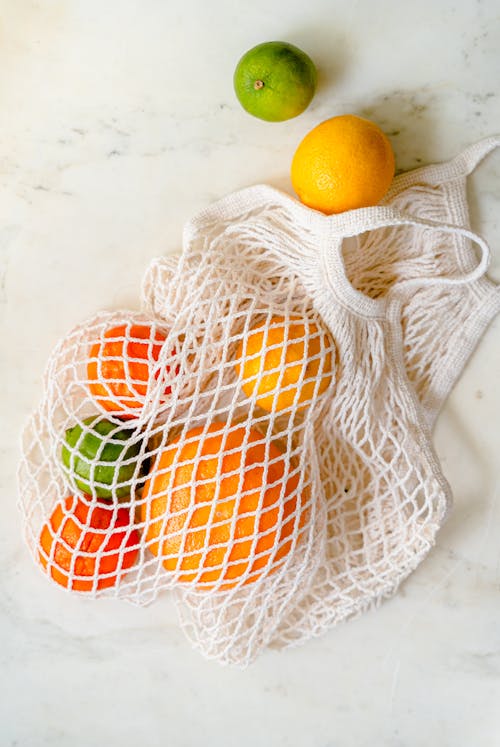 Free Overhead Shot of Tropical Fruits in a White Mesh Bag Stock Photo