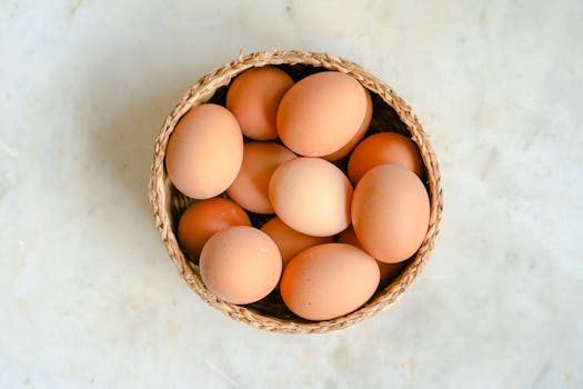 A top view of fresh brown eggs arranged in a woven basket on a marble surface, ideal for culinary concepts.