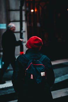 A person with a red beret and backpack explores the lively city streets.