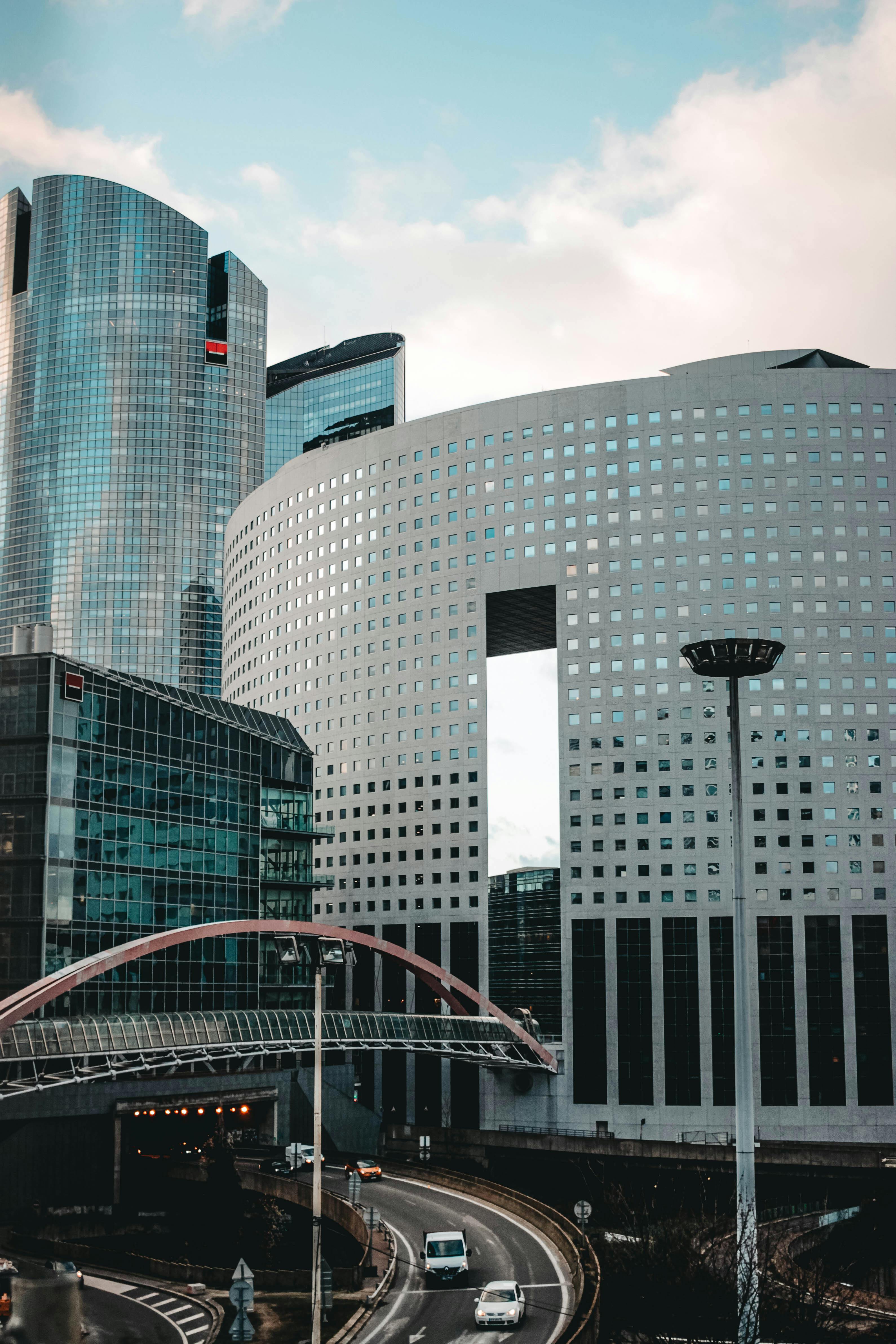 在现代城市区域的高塔旁，汽车行驶在柏油路上方