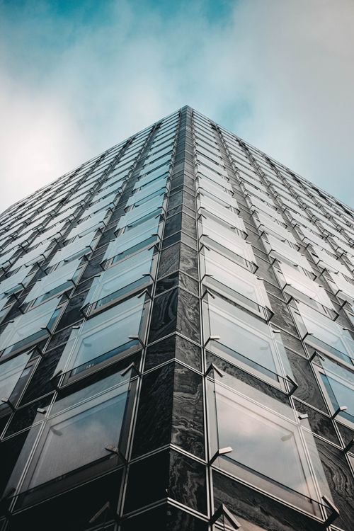 Free From below of contemporary high tower with glass mirrored walls against blue sky Stock Photo