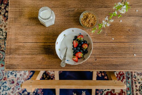 Free Aerial view of breakfast setup with a bowl of fresh fruits, milk, and granola on a wooden table. Stock Photo