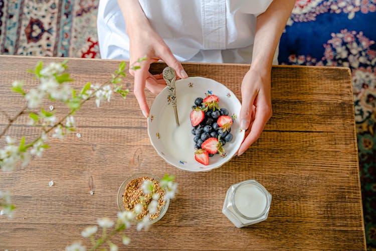 Hands Holding A Bowl With Milk And Berries