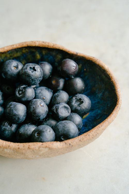 Free Close-up of fresh blueberries in a rustic bowl on a white background. Stock Photo