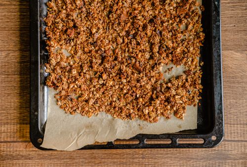 Free Golden brown granola fresh out of the oven on a parchment-lined baking tray, perfect for breakfast. Stock Photo