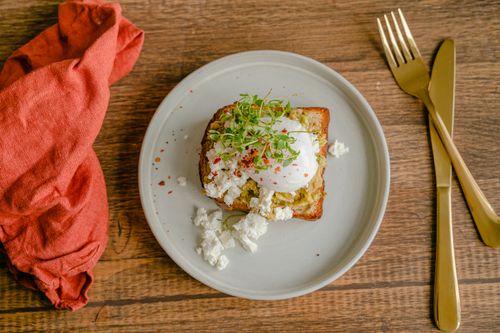 Free Avocado toast topped with a poached egg and microgreens on a rustic plate. Stock Photo