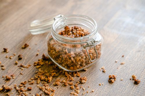 Free Homemade granola spilling from a glass jar, perfect snack idea. Stock Photo