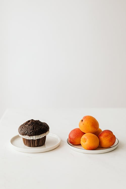 Chocolate muffin and fresh organic apricots placed on table
