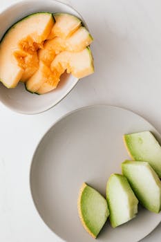 Top view of fresh cantaloupe and honeydew melon slices on a minimalist marble surface for a delicious and healthy snack.