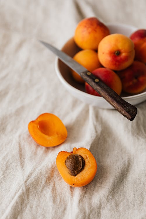 Delicious peaches and knife on white tablecloth