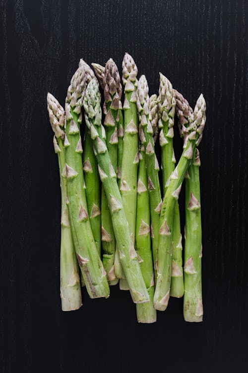 Free From above of fresh green asparagus placed on black wooden surface Stock Photo