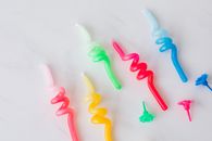 Closeup set of multicolored wax candles and holders for birthday placed on white marble background