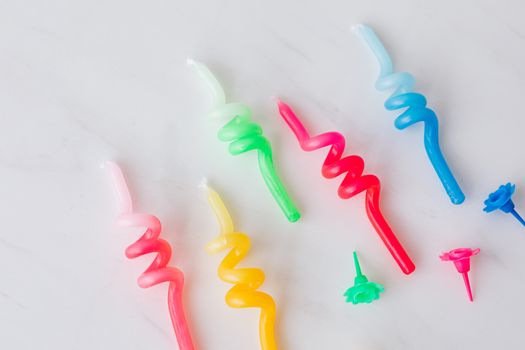 Closeup set of multicolored wax candles and holders for birthday placed on white marble background