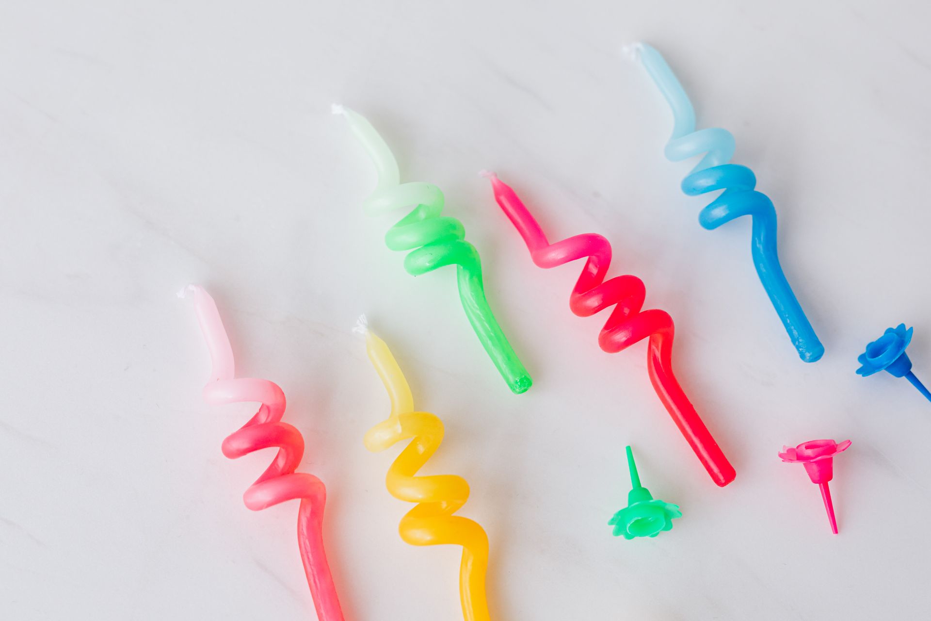 Closeup set of multicolored wax candles and holders for birthday placed on white marble background
