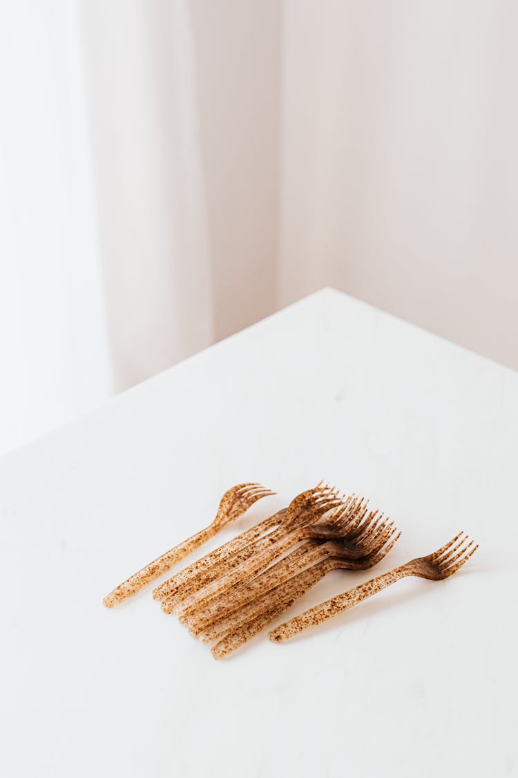 Set Of Golden Plastic Forks On White Table