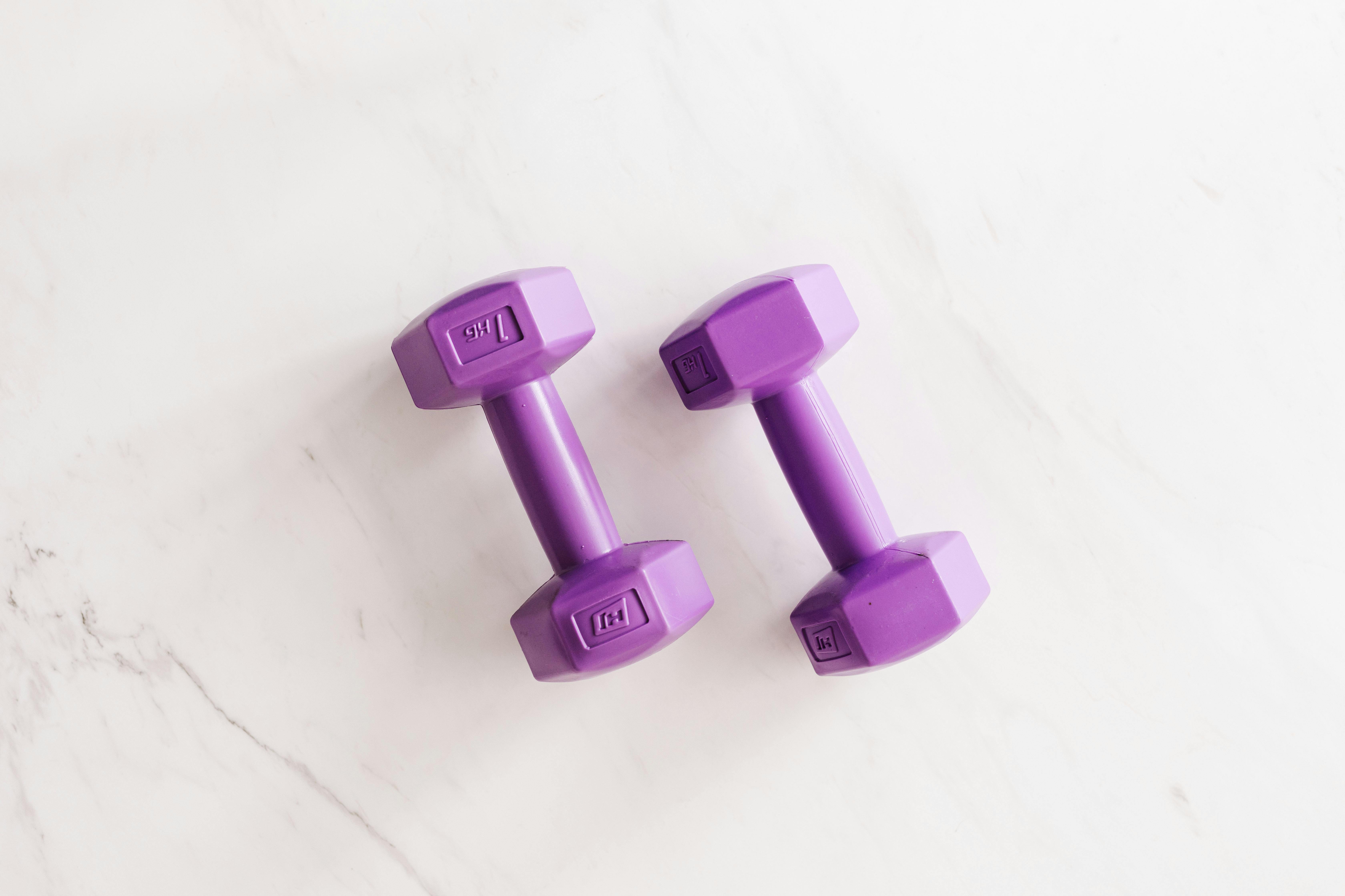 purple all cast dumbbells on marble surface