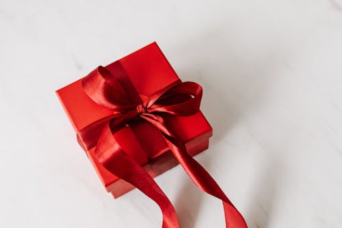 Free Red Gift Box With Red Ribbon on a White Surface  Stock Photo