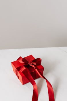 A red gift box with a satin bow on a marble surface, perfect for celebrations.