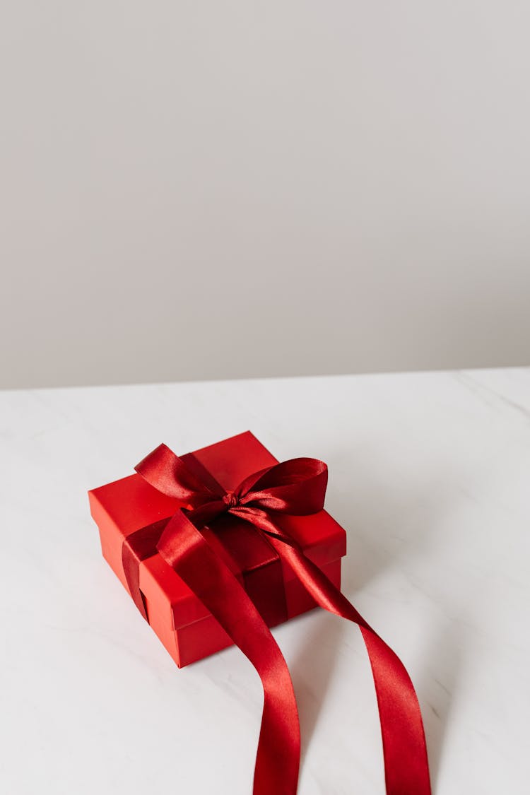 Red Gift Box With Red Ribbon On A White Surface 