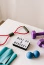 From above composition of dumbbells and massage double ball and tape and tubular expanders surrounding light box with wake up and workout words placed on white surface of table