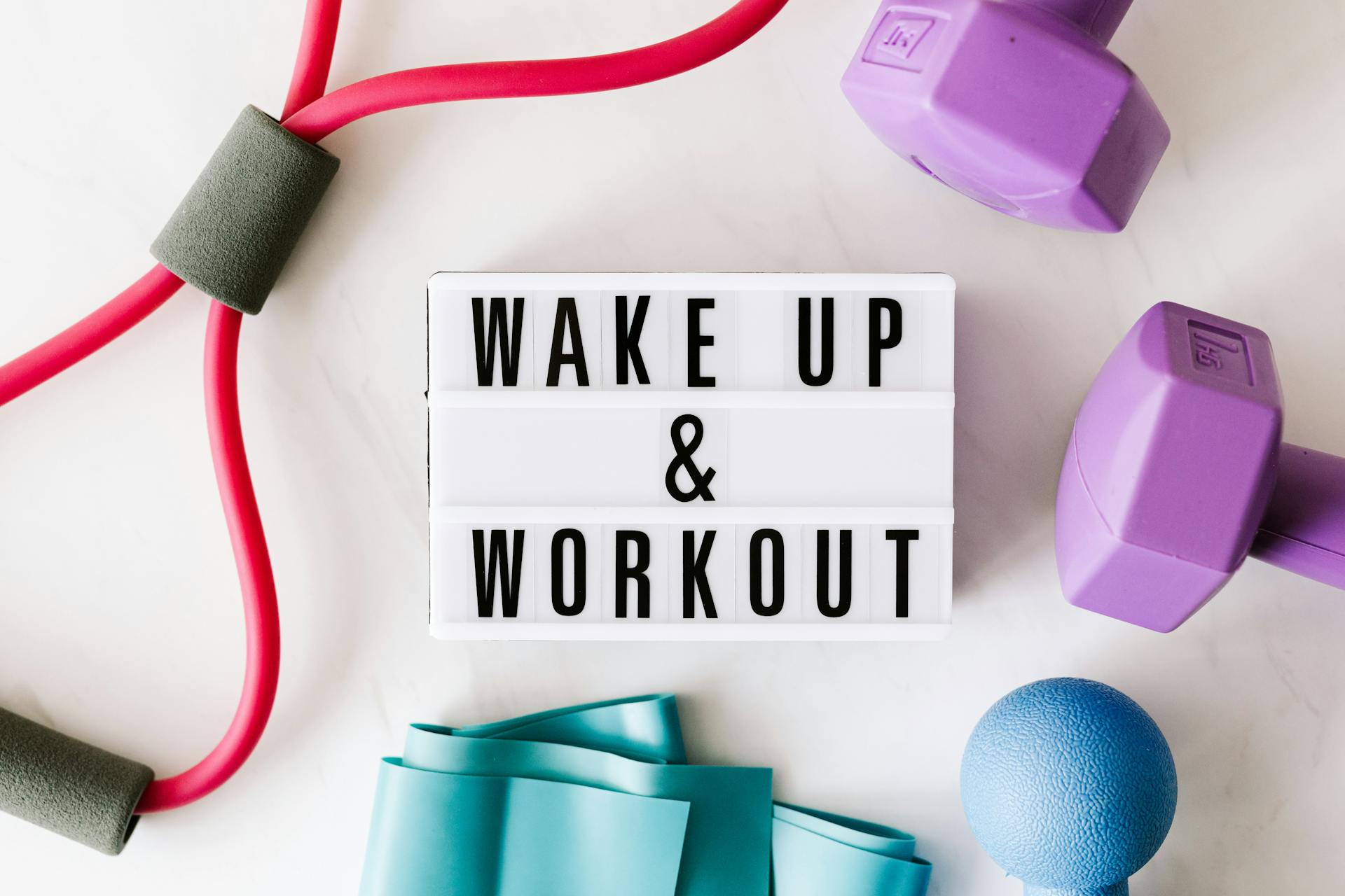 Wake up and workout title on light box surface surrounded by colorful sport equipment