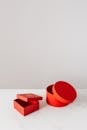 白色大理石桌子上，灰色背景前，放着几个空的红色礼品盒，有方形也有圆形，盒盖放在一旁