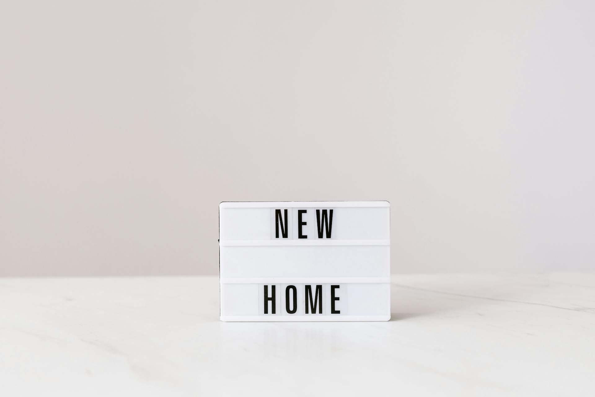 Minimalist lightbox with 'New Home' text on a modern gray background, perfect for real estate or interior design themes.