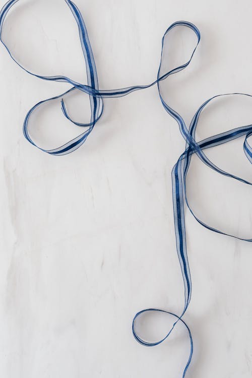 Free Top view of blue long ribbon chaotically placed on white marble surface of table Stock Photo
