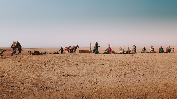 Group of people with camels in sandy desert