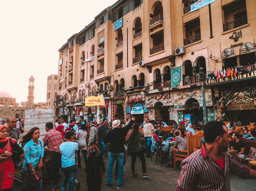 Crowded street of old city with people walking and resting in outdoor cafe