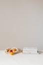 Composition of canvas bag with fresh ripe apricots placed on white table near stack of various books