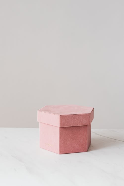 Free High angle of pink hexagon shaped gift box placed on white table against gray wall Stock Photo