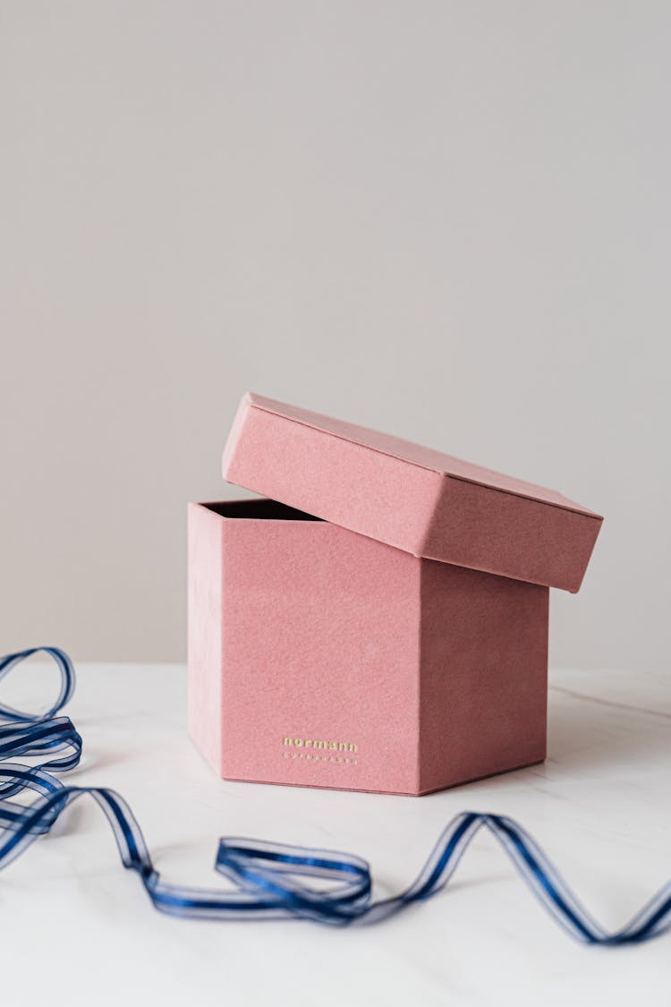 Half Opened Gift Box And Ribbon On White Table