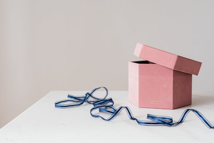 Pink Hexagon Present Box And Blue Ribbon On Table