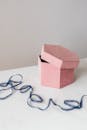 将那个原始的粉红色六边形礼品盒，放在系有蓝色欧根纱丝带的大理石桌子上