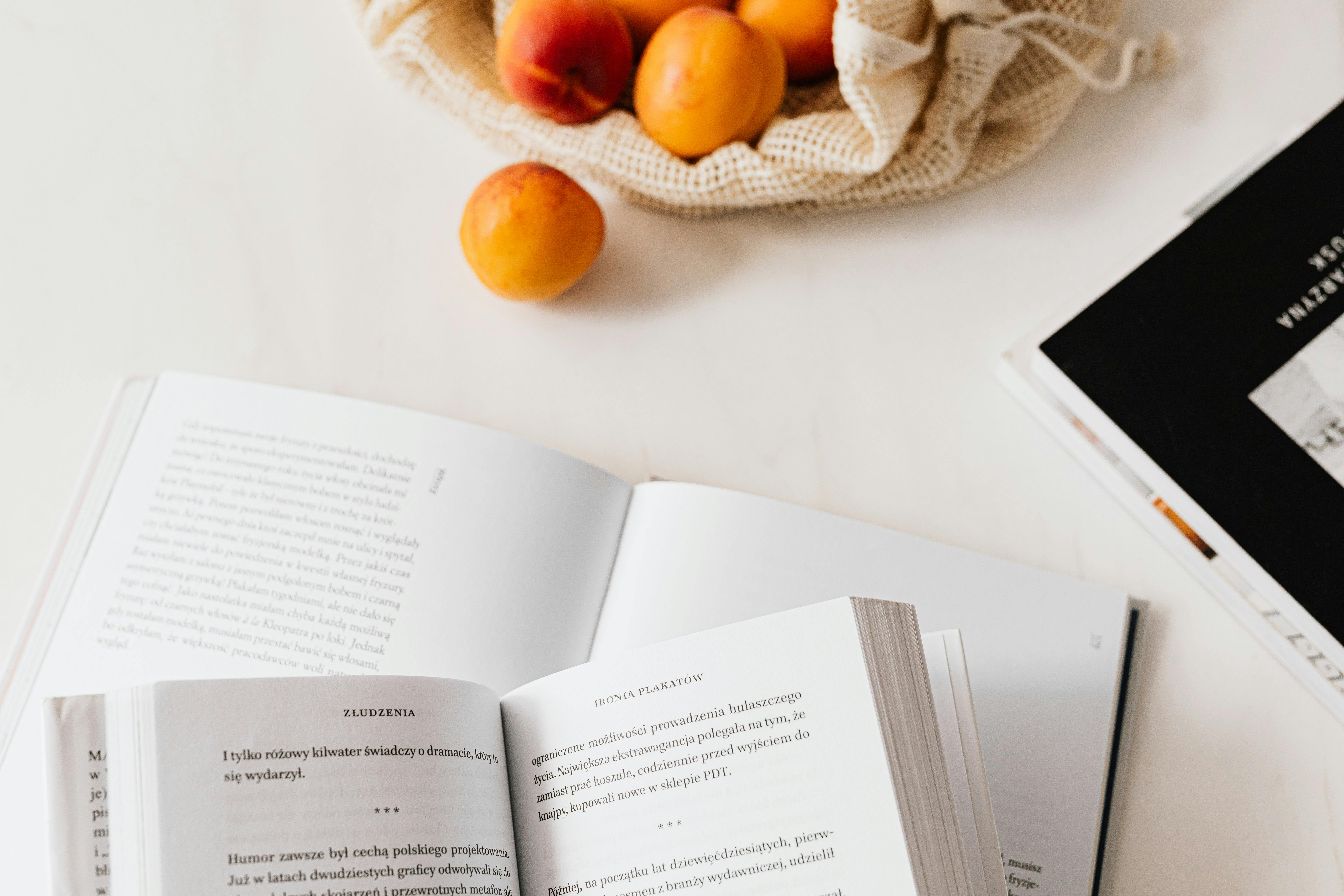 jute sack with appetizing ripe apricots placed on table with different books