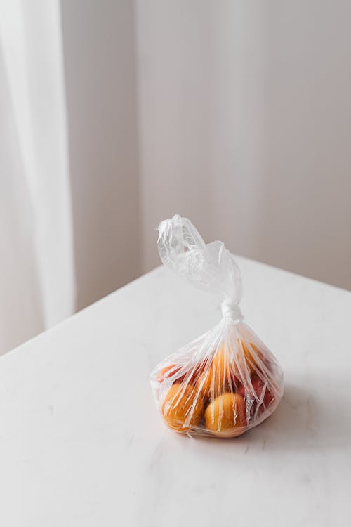 From above of fresh organic apricots in plastic bag placed on white table