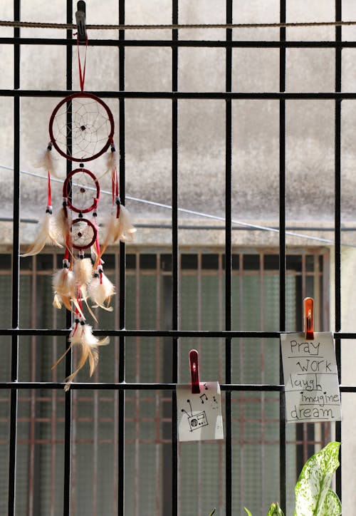 Metal bars on window decorated with hanging paper notes and dream catcher