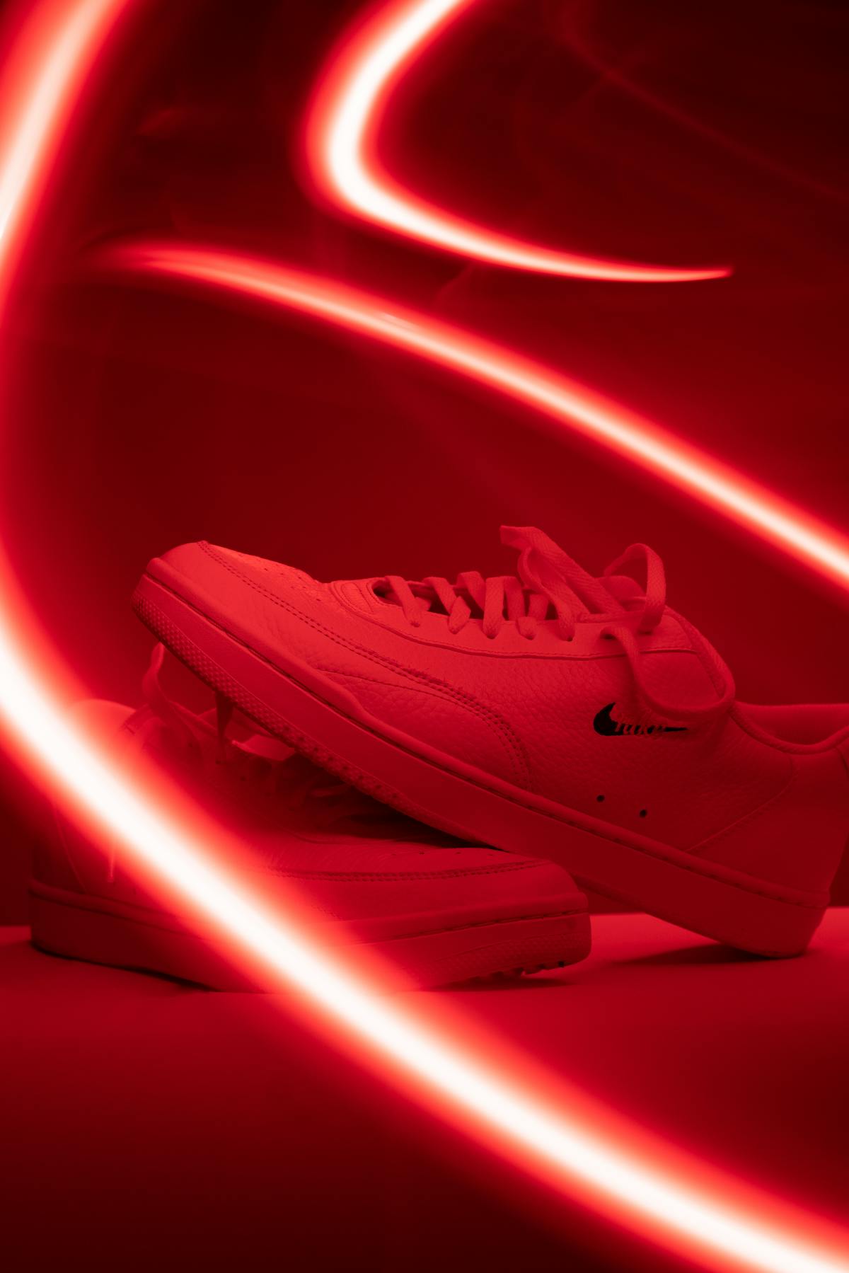 Primo piano laterale di sneaker Nike con luce rossa che mostra materiali.