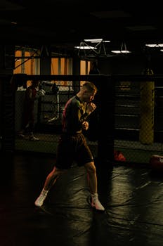 一名男性拳击手在光线昏暗的健身房里专注地练习着技术和动作