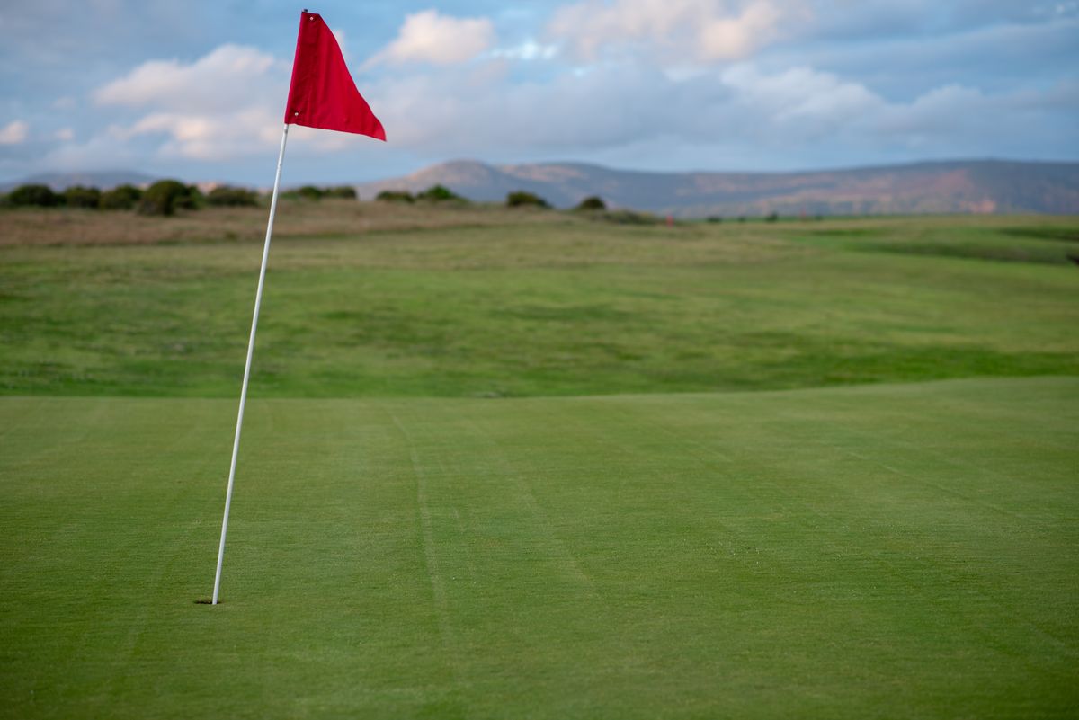 Golf course with a red flag on the green during a bright day