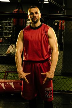 Strong muscular man posing confidently indoors in a gym.