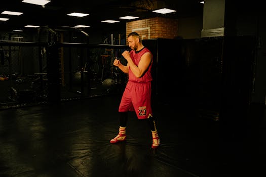 Athlete in boxing gym preparing for a fight with focused stance and intense expression.