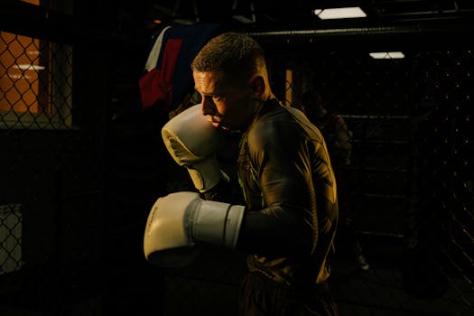 A focused boxer trains with gloves in a dimly lit gym, showcasing strength and determination.