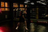 在昏暗的拳击馆里，一位敬业的拳击手正专注地磨练着自己的技能