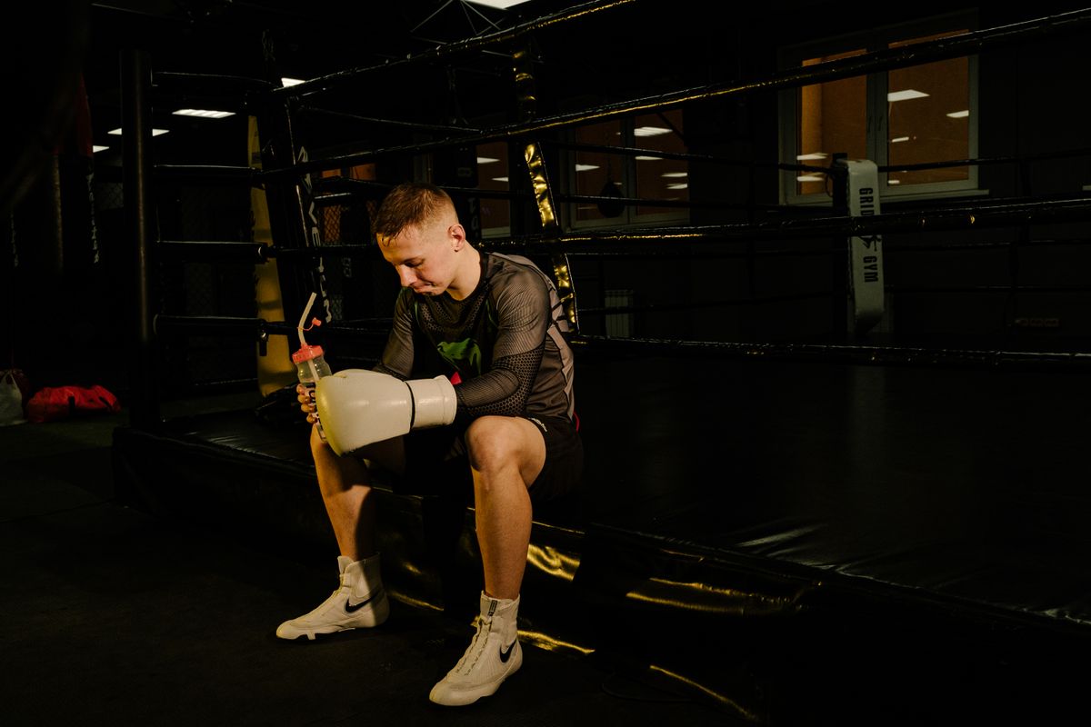 Boxer sitting in the ring with gloves and a water bottle after training